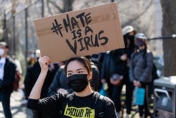 FILE - A woman rests a sign over her head while listening to speakers during a Rally Against Hate to end discrimination against Asian Americans and Pacific Islanders in New York City, March 21, 2021.