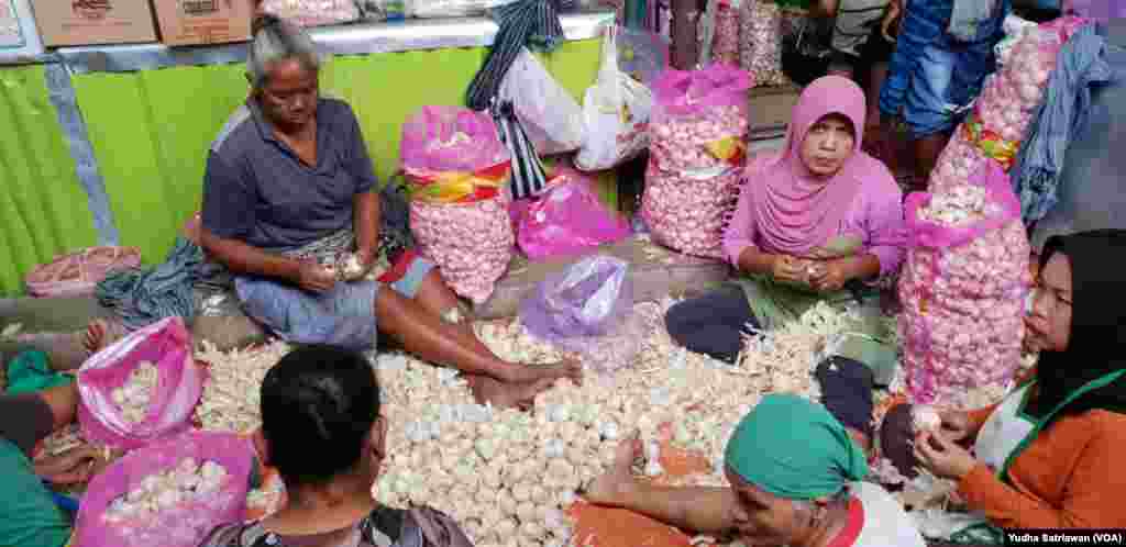 Sekelompok perempuan pengupas bawang putih bekerja di kompleks Pasar Legi di Solo, Kamis, 7 Maret 2019. (Foto: Yudha Satriawan/VOA)