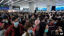 Passengers wear protective face masks at the departure hall of the high-speed train station in Hong Kong, Jan. 23, 2020. 