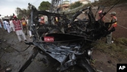 Pakistani officials and rescue workers gather at the site of a car bombing in Peshawar, Pakistan on Monday, Sept. 3, 2012. 