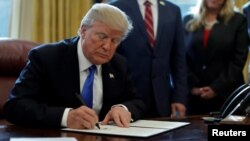 FILE - U.S. President Donald Trump signs documents in the Oval Office of the White House in Washington, Jan. 9, 2018. 