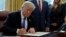 FILE - U.S. President Donald Trump signs documents in the Oval Office of the White House in Washington, Jan. 9, 2018. 