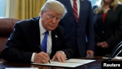U.S. President Donald Trump signs an Executive Order on "Supporting our Veterans during their Transition from Uniformed Service to Civilian Life" in the Oval Office of the White House in Washington, Jan. 9, 2018. 
