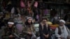 Taliban fighters sit next to street vendors at a local market in Kabul, Afghanistan, Friday, Sept. 10, 2021. (AP Photo/Felipe Dana)