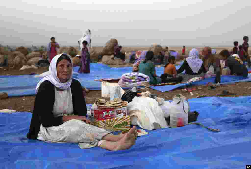 FILE - In this Sunday, Aug. 10, 2014 file photo, displaced Iraqis from the Yazidi community settle at a camp at Derike, Syria.