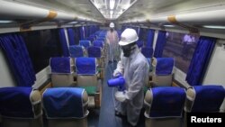 Seorang petugas menyemprotkan cairan disinfektang di dalam kereta untuk mencegah penyebaran virus corona (COVID-19), di Surabaya, Jawa Timur, 15 Maret 2020. (Foto: Reuters)