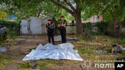 In this photo provided by the National Police of Ukraine on Aug. 27, 2024, police officers stand next to bodies covered with plastic bags after a Russian airstrike in Zaporizhzhia, Ukraine.