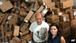 Catholic Charities of the Rio Grande Valley staffer Eli Fernandez and volunteer Natalie Montelongo stand by a pile of unsorted Amazon boxes packed with donations in McAllen, Texas, June 24, 2018.