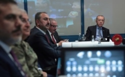 Turkey's President Recep Tayyip Erdogan, right, with military and Intelligence chiefs, ministers and his ruling party members in an operations room at the presidential palace, in Ankara, Turkey, Oct. 9, 2019.