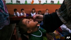 FILE - A health worker administers a polio vaccine to a child at a school in Peshawar, Pakistan, Sept. 9, 2024. 