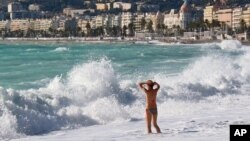 FILE - A woman wades into the Mediterranean surf in Nice, southeastern France. The World Travel and Tourism Council reports that while the sector is resilient globally, it's falling short of expectations in France, Turkey and Brazil. 