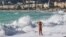 FILE - A woman wades into the Mediterranean surf in Nice, southeastern France. The World Travel and Tourism Council reports that while the sector is resilient globally, it's falling short of expectations in France, Turkey and Brazil. 