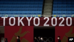 Staf berjalan di bawah logo Tokyo 2020 di lapangan permainan judo di Nippon Budokan menjelang Olimpiade Musim Panas 2020, Jumat, 23 Juli 2021, di Tokyo, Jepang. (Foto: AP/Vincent Thian)