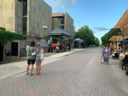 A Charlottetown street is of interest to a couple looking at the crowded bar patios. (Jay Heisler/VOA)