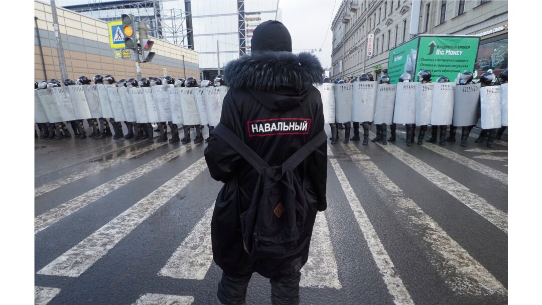 Un hombre con un letrero que dice 'Navalny' en la espalda se para frente a policías antidisturbios que bloquean el camino a una protesta contra el encarcelamiento del líder opositor Alexei Navalny en San Petersburgo, Rusia, el 31 de enero de 2021.