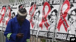 FILE - A man talks on a mobile phone as he walks past World AIDS Day banners in Johannesburg, South Africa, Dec. 1, 2014.