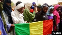 People seeking refuge from Tuareg separatist rebel group MNLA display a Malian flag in a military camp in the northern town of Kidal, July 17, 2013.