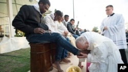 Le pape François embrasse le pied d'un homme lors du rituel du lavage des pieds au centre des réfugiés de Castelnuovo di Porto, à environ 30 km de Rome, le 24 mars 2016.