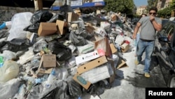 A man covers his nose as he walks past a pile of garbage along a street in Beirut, July 22, 2015.