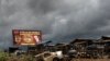FILE - The wreckage of burnt-out car is pictured, allegedly destroyed by separatist fighters in a recent attack, as a Cameroonian soldier patrols the edge of the abandoned market in the majority anglophone Southwest province in Buea, Oct. 3, 2018. 