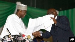 Independent National Electoral Commission chairman, Attahiru Jega, left, views election documents at the coalition center in Abuja, Nigeria, Monday, March 30, 2015, as votes are collated for last Saturday's elections, in Abuja. In a cliffhanger of an elec