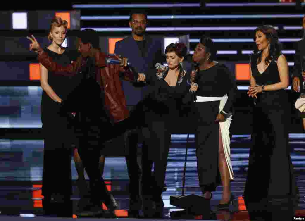 Sharon Osborne kicks at an unidentified man who interrupted the acceptance speech by the cast of her show &quot;The Talk,&quot; who won the award for favorite daytimeTV hosting team, at the People&#39;s Choice Awards 2016 in Los Angeles, California, Jan. 6, 2016.