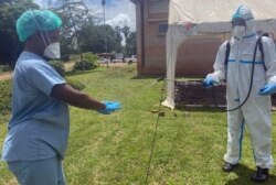 A health worker disinfects a colleague at Wilkins Hospital in February of 2021 when COVID-19 jabs there were still available. (Columbus Mavhunga/VOA)