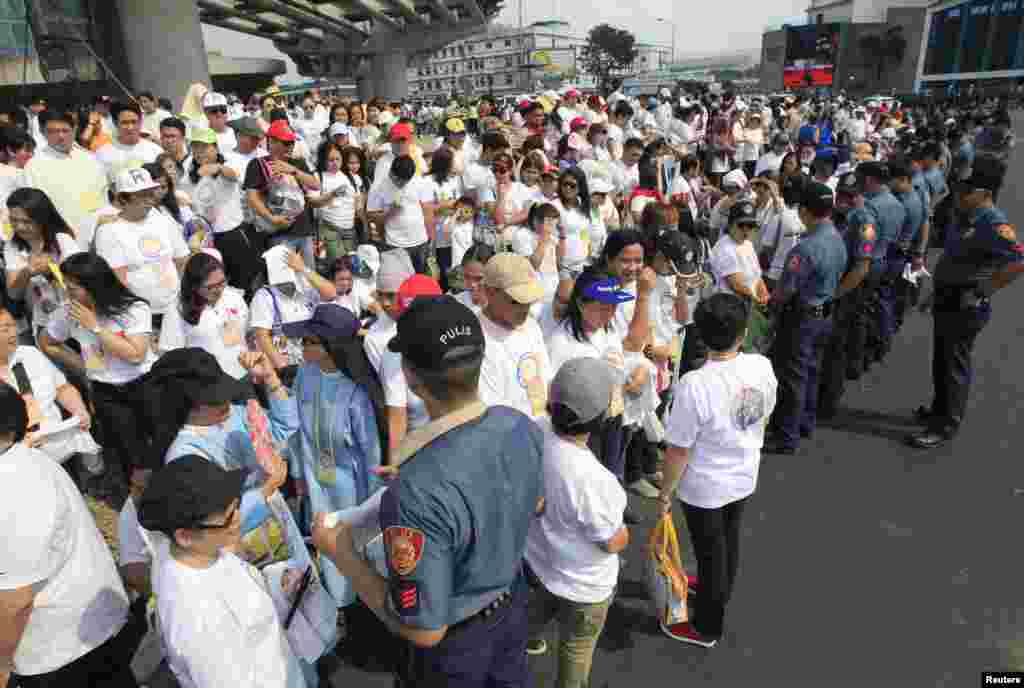 Para anggota kepolisian nasional Filipina berjaga-jaga di depan khalayak ramai yang menanti kedatangan Paus Fransiskus di Manila (15/1). (Reuters/Romeo Ronoco)