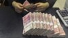 FILE - A clerk counts 100 Chinese yuan banknotes at a branch of China Merchants Bank in Hefei, Anhui province April 20, 2015.