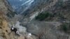 Orang-orang berjalan melewati bendungan yang hancur setelah gletser Himalaya pecah dan menabrak bendungan di Desa Raini Chak Lata di distrik Chamoli, negara bagian utara Uttarakhand, India, 7 Februari 2021. (Foto: Reuters)