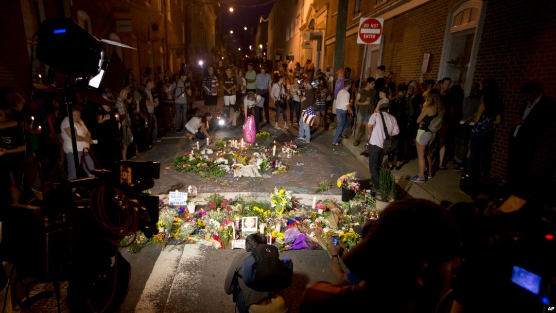 Cahaya kamera TV menerangi tumpukan bunga tanda belasungkawa dalam doa bersama di Charlottesville, Virginia, Minggu, 13 Agustus 2017 untuk memperingati korban luka dan meninggal dalam aksi protes sehari sebelumnya. 