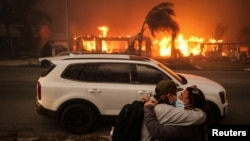 Warga tampak berpelukan saat mereka berupaya mengevakuasi wilayah Altadena, California, menyusul kebakaran hutan yang meluas di negara bagian tersebut pada 8 Januari 2025. (Foto: Reuters/David Swanson)