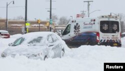 An ambulance passes an abandon car during a winter storm that hit the Buffalo region, in Amherst, New York, Dec. 26, 2022. 