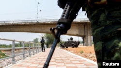 200明缅甸军人在反政府武装攻打妙瓦底数日后撤至通向泰国的一座大桥，泰国军人守卫在本国边境一侧。(2024年4月11日)