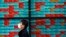 FILE - A man walks past an electronic stock board showing Japan's Nikkei 225 index at a securities firm in Tokyo, Japan, April 8, 2020.