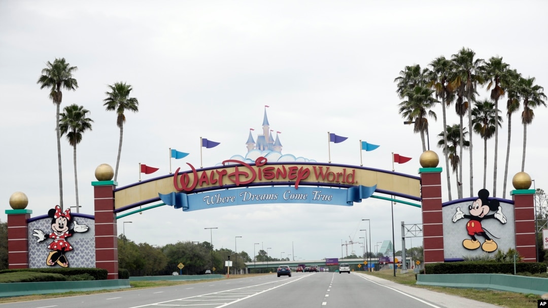 FILE - The road to the entrance of Walt Disney World is nearly empty as the theme park has been closed since mid-March because of the new coronavirus, in Lake Buena Vista, Fla., March 16, 2020.