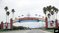 FILE - The road to the entrance of Walt Disney World is nearly empty as the theme park has been closed since mid-March because of the new coronavirus, in Lake Buena Vista, Fla., March 16, 2020.
