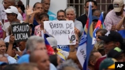 Un letrero de un manifestante antichavista en el que se lee "basta de apagones" es visto en medio de una concentración a favor del candidato presidencial opositor Edmundo González Urrutia en La Victoria, Aragua, el 18 de mayo de 2024.