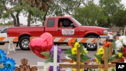 Un pasajero en una camioneta mira un sitio conmemorativo, el 8 de mayo de 2023, donde ocho migrantes murieron y varios resultaron heridos el día anterior, domingo, mientras esperaban en una parada de autobús en Brownsville, EEUU.
