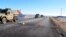 A convoy of armored vehicles and SUVs rolls past a barricade on the road near the Malheur National Wildlife Refuge near Burns, Ore., Jan. 30, 2016.