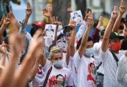 Myanmar citizens show the three-finger salute during a protest against the military coup in Myanmar outside United Nations venue in Bangkok, Thailand, Feb. 7, 2021.