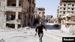 FILE - A British volunteer fighter of Syrian Democratic Forces runs for cover to avoid sniper fire of Islamic State militants, at the front line in Raqqa, Syria, Oct. 7, 2017. 