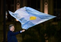Argentina's President and presidential candidate of the Juntos por el Cambio party Mauricio Macri waves a national flag during the closing rally of his campaign in Cordoba, Argentina, Oct. 24, 2019.