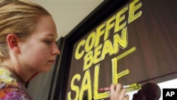 Carrie Warden, manager of The Sconelady's Coffee Shop, paints a sign for their fall coffee sale in Lawrence, Kan. Americans' confidence in the economy rose only slightly in October from September, according to a monthly survey, as they continue to grapple