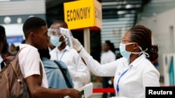 FILE PHOTO: A health worker checks the temperature of a traveller as part of the coronavirus screening procedure at the Kotoka International Airport in Accra, Ghana January 30, 2020. REUTERS/Francis Kokoroko/File Photo