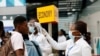 FILE - A health worker checks the temperature of a traveler as part of the coronavirus screening procedure at the Kotoka International Airport in Accra, Ghana, Jan. 30, 2020.