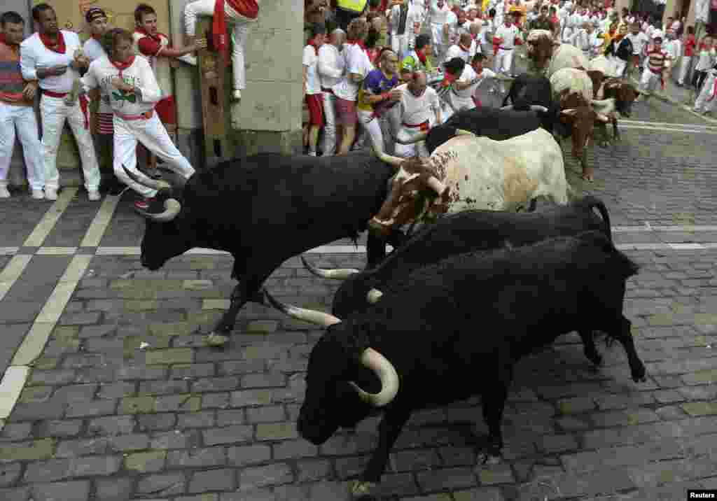 Runners sprint alongside Valdefresno fighting bulls at the Estafeta corner during the third running of the bulls of the San Fermin festival in Pamplona July 9, 2013. Two runners were treated in hospital for bruising following the run that lasted two minut