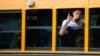 Un inmigrante pate de un grupo que acababa de arribar saluda desde la ventanilla de un bus escolar en Edgartown, Massachusetts, el 14 de septiembre del 2022. (Ray Ewing/Vineyard Gazette vía AP)