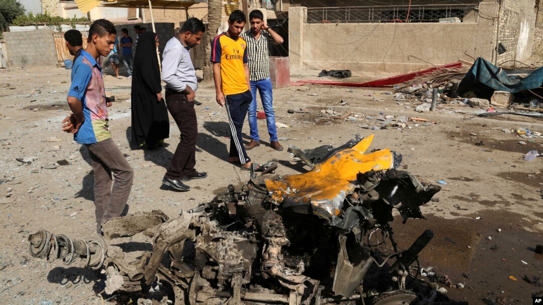 Warga setempat memeriksa lokasi serangan bom mobil di distrik Mashtal, Baghdad, Irak hari Minggu (27/10). 