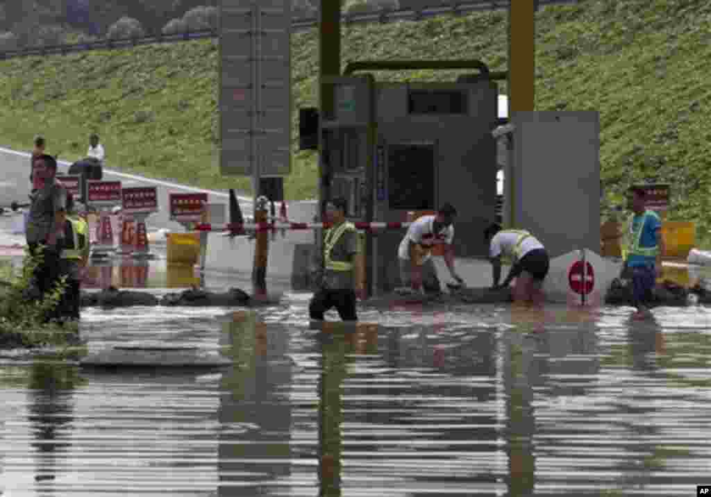 7月23日，工人们在北京房山区一个公路收费站外堆沙包，以防大水泛滥。中国首都遭遇60年不遇大雨，北京遭到水淹，官方称79人丧生。（美联社照片）
